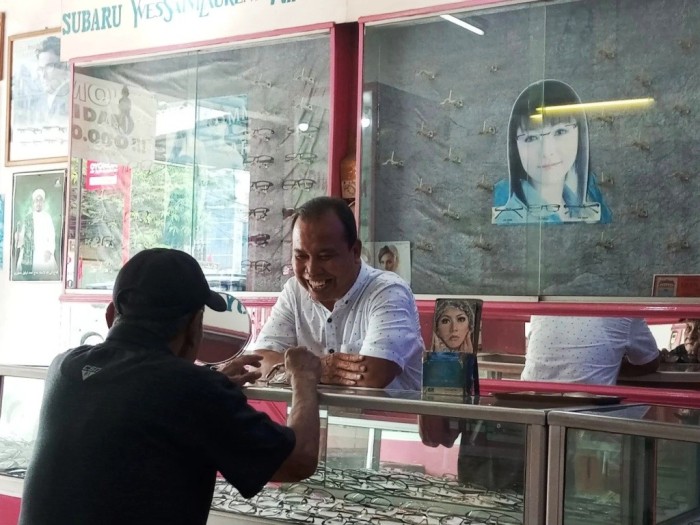 Uda Andi, Owner Optik Sriwijaya, sedang melayani pelanggan yang datang untuk membeli kacamata. (URANGMINANG.ID/SIKUMBANG)